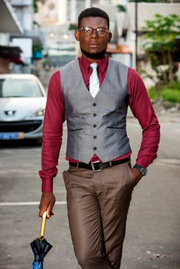 Yakışıklı genç işadamı sokakta yürürken elinde şemsiyeyle dolaşıyor.