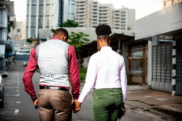 back view of a beautiful young african couple walking in the street outdoors