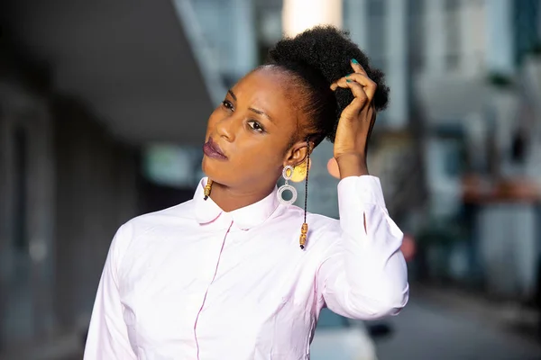 stock image charming young african woman standing outdoors scraping her hair.