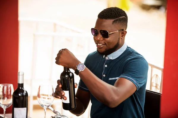 handsome young man wearing sunglasses sitting with bottles of red