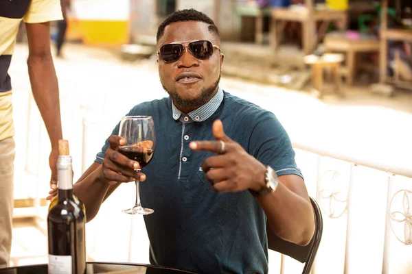 handsome young man wearing sunglasses sitting with bottles of red