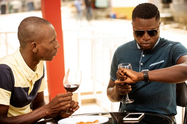 two young friends talking near a restaurant drinking a glass of red wine