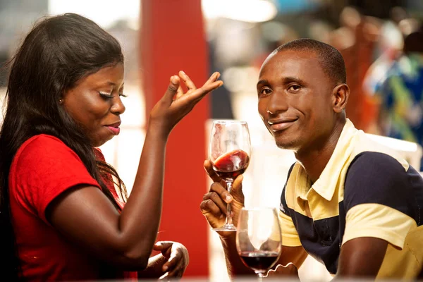 若いカップルがワインを共有するためにリフレッシュバーの外に座って笑顔で — ストック写真