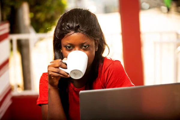 ノートパソコンで仕事をしながらコーヒーを飲みながらコーヒーショップの外で働いている美しい穏やかな若い女性 — ストック写真