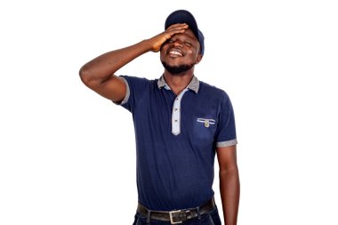 Genç adam, beyaz arka planda şapkasını takıp gülüyor..