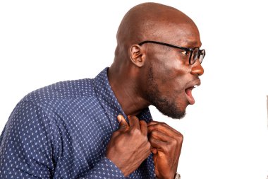 Gözlüklü yakışıklı genç adam ellerini gömleğinin yakasında tutuyor ve ağzı açık bir şekilde yan tarafa bakıyor.