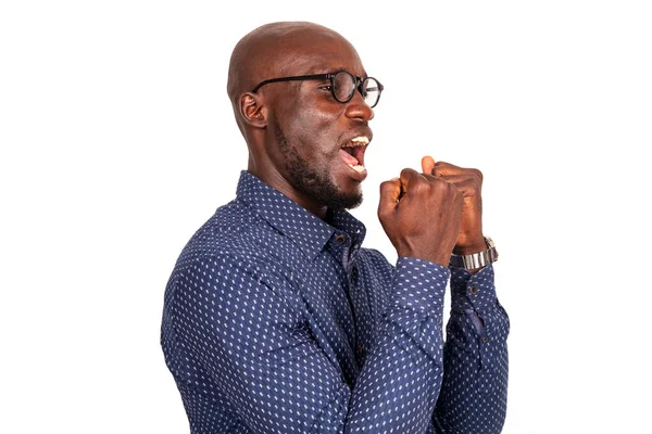 Beyaz arka planda duran yakışıklı genç işadamı mutlu ve heyecanlı bir şekilde kollarını kaldırıp, gülümseyerek ve başarı için bağırarak zafer jesti yapıyor.