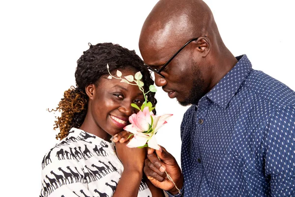 Beyaz arka planda duran genç adam kız arkadaşına çiçek sunuyor.