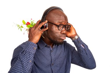 Genç adam beyaz arka planda durup kulaklık kullanarak müzik dinliyor.