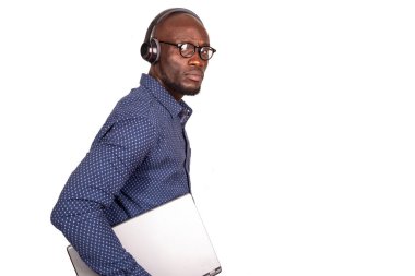 Beyaz arka planda duran yakışıklı iş adamı, elinde dizüstü bilgisayarla kameraya bakıyor.