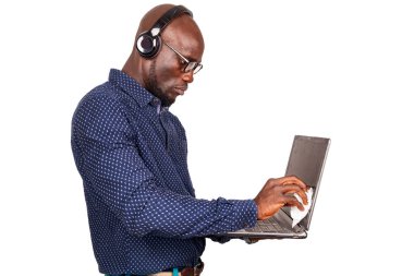 Beyaz arka planda duran, dizüstü bilgisayarını temizleyen ve kulaklık takan yakışıklı bir iş adamı