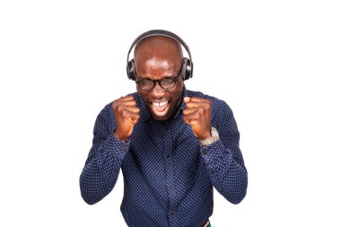 Genç yakışıklı adam kulaklık takıyor ve çılgın ve sürpriz bir başarıyı kutluyor kolları havada ve gözleri kapalı bağırıyor heyecanla