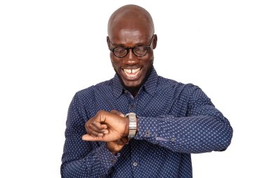 Beyaz arka planda gözlüklü yakışıklı iş adamı gülerken saatine bakıyor.