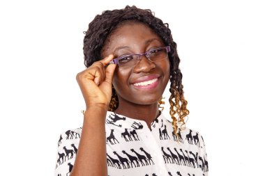 Beyaz arka planda duran, gözlüklü ve gülümseyen kameraya bakan güzel bir genç kadın.