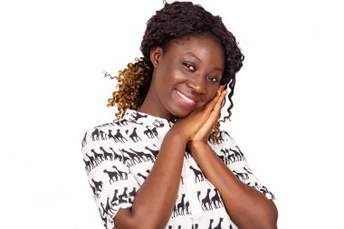 Genç ve güzel bir kadın ellerini yanaktan geçirip gülümseyerek kameraya bakıyor.