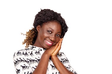 Genç ve güzel bir kadın ellerini yanaktan geçirip gülümseyerek kameraya bakıyor.