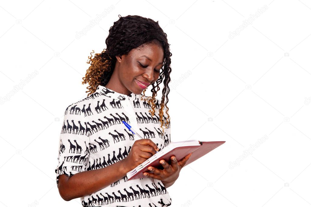 Pretty young beautiful woman standing, writing, taking notes, holding a red notepad in her hand and a pen and smiling