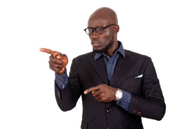 Beyaz arka planda duran yakışıklı, takım elbiseli genç bir işadamı parmağına bir şey doğrultuyor..
