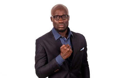 Beyaz arka planda duran yakışıklı, takım elbiseli genç bir işadamı göğüsteki kamera yumruğuna bakıyor..