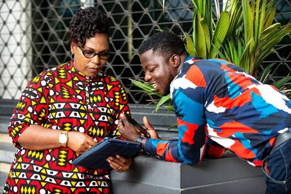 two business people using a mobile phone outside. man with mobile phone and adult woman working on tablet digital