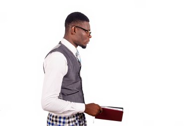 Genç işadamı kırmızı bir günlük tutarak yan yana duruyor ve beyaz arka planda izole edilmiş kameraya bakıyor.