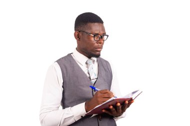 Beyaz arka planda duran yelek giymiş yakışıklı bir işadamı günlüğünü tutarken