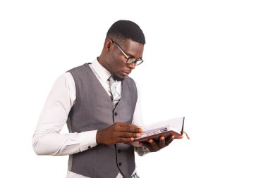 Hayat ceketli yakışıklı genç iş adamı beyaz arka planda izole edilmiş, ajandasını kontrol ediyor.