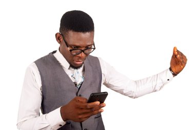 Gri bir yelek ve gözlük takan yakışıklı genç işadamı kolunu hareket ettirirken cep telefonu kullanıyor.