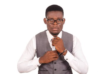 Ciddi bir iş adamı gri bir yelek giyiyor ve kameraya bakarken kravatını düzeltiyor.