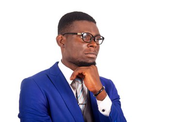 Mavi takım elbiseli, el ele tutuşan, düşünen ve yan gözle bakan çekici genç iş adamının yan görüntüsü.