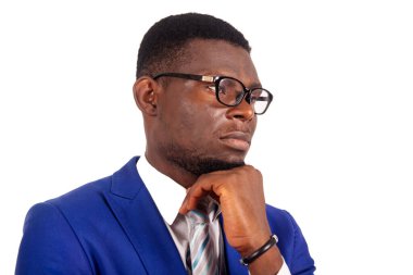 Mavi takım elbiseli, el ele tutuşan, düşünen ve yan gözle bakan çekici genç iş adamının yan görüntüsü.