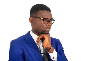 Mavi takım elbiseli, el ele tutuşan, düşünen ve yan gözle bakan çekici genç iş adamının yan görüntüsü.