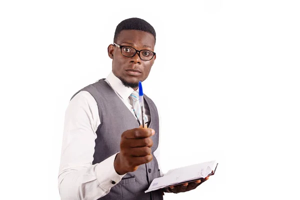 日記をつけたペンを見せる白い背景のベストに立つハンサムなビジネスマン — ストック写真