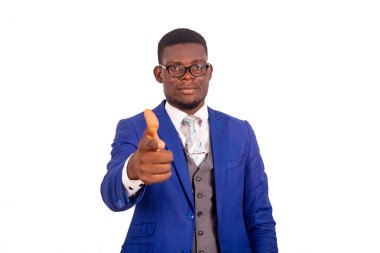 Ceketli yakışıklı genç işadamı beyaz arka planda tek başına duruyor ve baş parmağını gösteriyor.