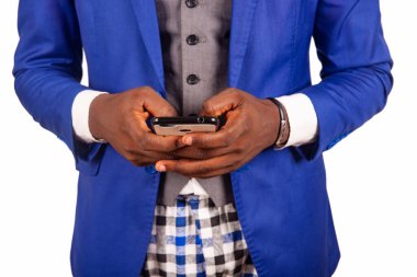 Ceketli genç işadamı beyaz arka planda cep telefonuyla tek başına duruyor.