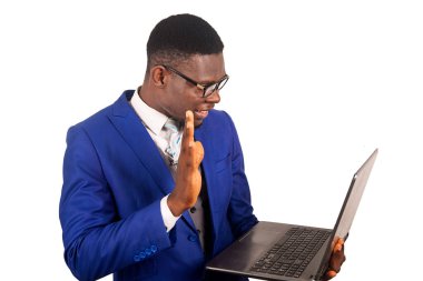 Takım elbiseli yakışıklı genç bir iş adamı beyaz bir arkaplanda izole bir şekilde dizüstü bilgisayar kullanarak iletişim kuruyor ve gülümsüyor.