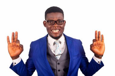 Gözlüklü, mavi ceketli yakışıklı genç bir işadamı parmaklarıyla jest yapıyor ve kameraya gülümsüyor.