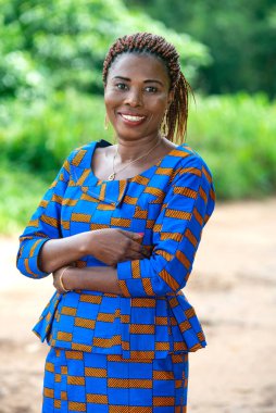 Güzel, yetişkin bir iş kadını kollarını kavuşturup kameraya bakıp gülümsüyor..