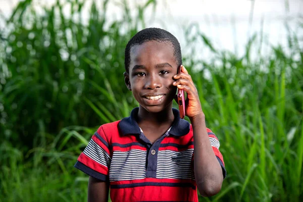 Joven Camiseta Pie Parque Comunicándose Con Teléfono Móvil Mirando Cámara — Foto de Stock