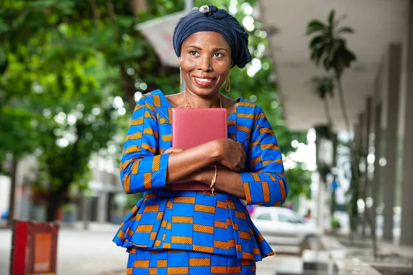 Geleneksel Kıyafetli Güzel Afrikalı Kadını Dışarıda Kameraya Gülümserken Elinde Bir — Stok fotoğraf