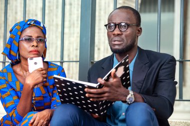 Takım elbiseli yakışıklı bir işadamı elinde bir not defteri tutarken ortağını düşünüyor..