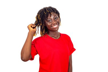 Kırmızı elbiseli güzel bir kadın kıvırcık saçlarından bir tutam tutuyor ve kameraya gülümsüyor..