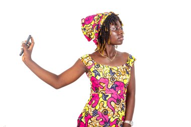 Güzel, ciddi, genç bir kadın cep telefonu ekranını yandan gösteriyor. Yüzü sola dönüyor..