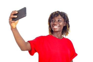 Kırmızı tişörtlü güzel bir kadın beyaz arka planda duruyor cep telefonuna bakıp gülümsüyor..