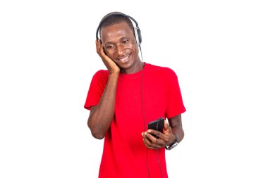 Tişört giyen yakışıklı yetişkin bir adam kulaklıkla müzik dinliyor cep telefonuyla gülümsüyor..