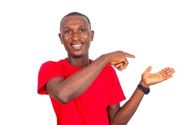 Genç adam beyaz arka planda duruyor. Yönünü gösteriyor ve gülümsüyor..