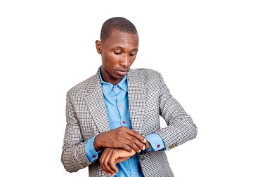 Ceketli genç bir işadamı beyaz arka planda durup saatine bakıyor..