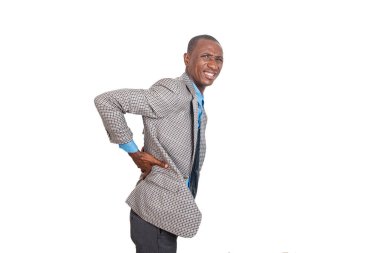 Beyaz arka planda duran ceketli genç işadamı kalça ağrısı çekiyor..