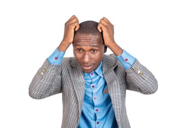 Beyaz arka planda duran ceketli genç işadamı ellerini başının üstüne koyuyor..