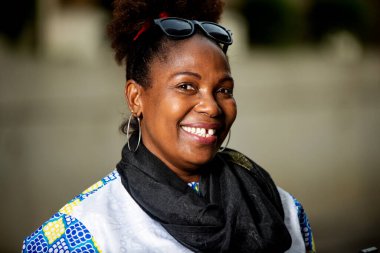 Sokakta boynuna fular dolanmış ve kameraya gülümseyen olgun bir iş kadını..